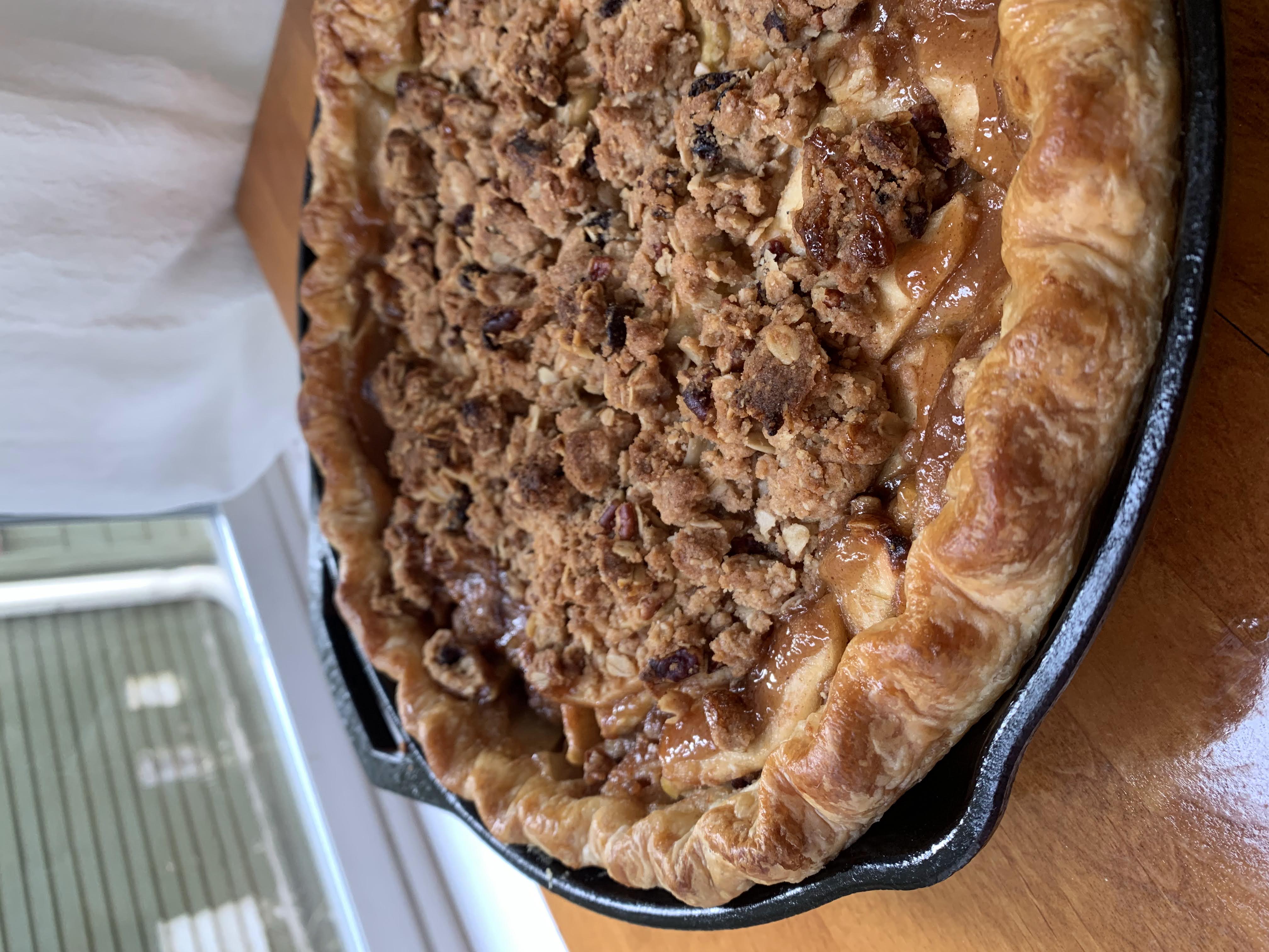 Apple pie baked in a cast iron pan and topped with dried fruit and nut streusel.