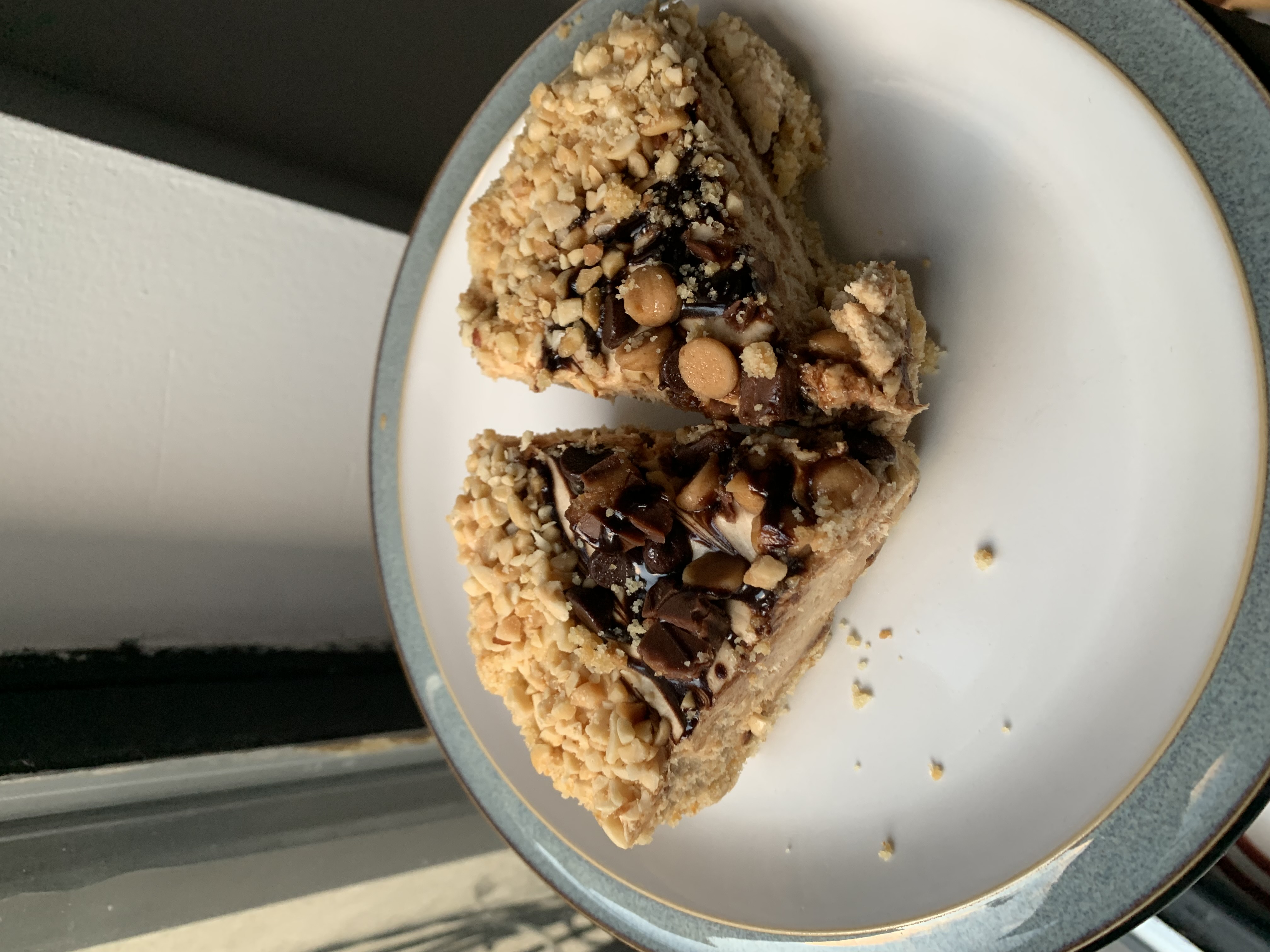 Two slices of peanut butter pie topped with chocolate syrup, peanut butter chips, and crushed peanuts.